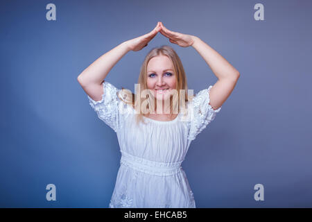 Ragazza bionda aspetto europeo in un abito bianco piegato la sua mano Foto Stock