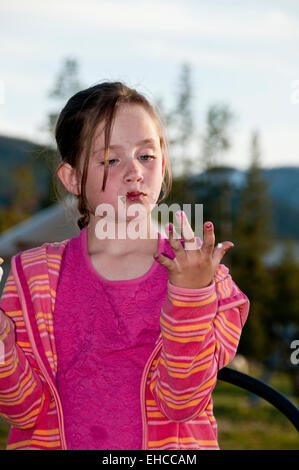 Ragazza giovane leccarsi le dita dopo aver mangiato una s'more (MR) Foto Stock