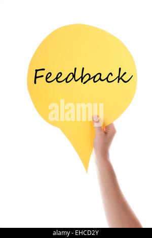 Una mano che tiene un discorso giallo palloncino o discorso bolla con testo in inglese Feedback isolato su bianco Foto Stock