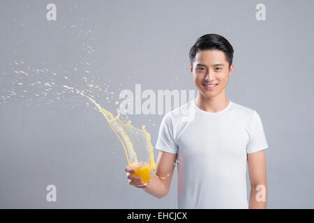 Giovane uomo con spruzzi di succo d'arancia Foto Stock