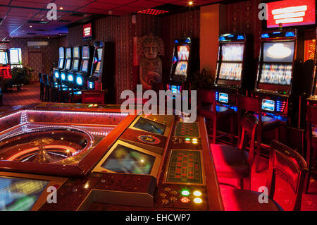 Tavolo da Roulette e slot machine. Illuminato rosso casino. Foto Stock