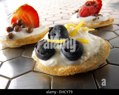 Dolce blinis canipe, blini e rabboccato con creme fraiche, fetta di fragola e scaglie di cioccolato e di mirtilli freschi Foto Stock