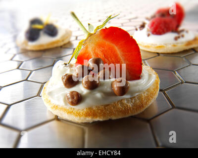 Dolce blinis canipe, blini e rabboccato con creme fraiche, fetta di fragola e scaglie di cioccolato Foto Stock