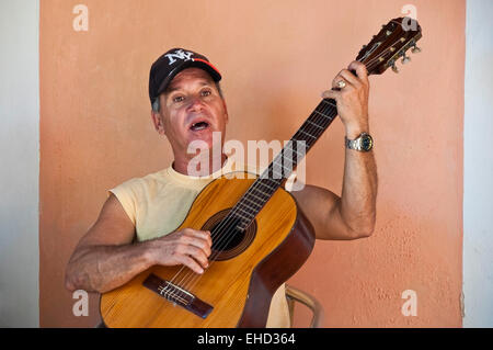 Ritratto orizzontale di un uomo suonare la chitarra spagnola e cantando su un angolo di strada in Cuba Foto Stock