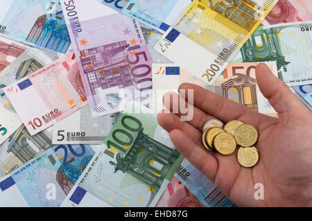 Il conteggio di Euro (EUR) monete, con le banconote in euro in background. Il concetto di business. Foto Stock