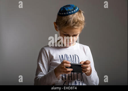 Ritratto in studio di ragazzo bianco con gli Ebrei kipa yarmulke o con il telefono cellulare Foto Stock