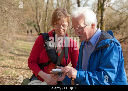 Uomo che mostra le immagini sulla sua fotocamera digitale per la donna al fiume Elba vicino Sandkrug, Schnakenbek, Schleswig-Holstein, Germania Foto Stock