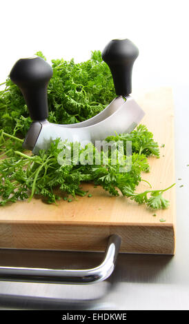 Prezzemolo tritato sul taglio di legno Foto Stock