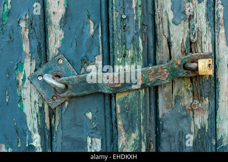 In legno antico porta verde con lucchetto arrugginito. Foto Stock