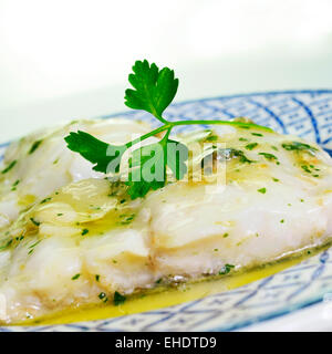 Una piastra con Bacalao al pil-pil, una tipica ricetta spagnola di baccalà con aglio e prezzemolo Foto Stock