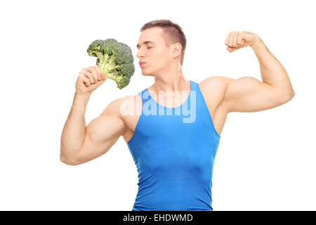 Uomo muscolare baciando un enorme pezzo di broccoli isolati su sfondo bianco Foto Stock