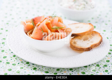 Salmone selvaggio affumicato e baguette sulla piastra bianca, il fuoco selettivo Foto Stock