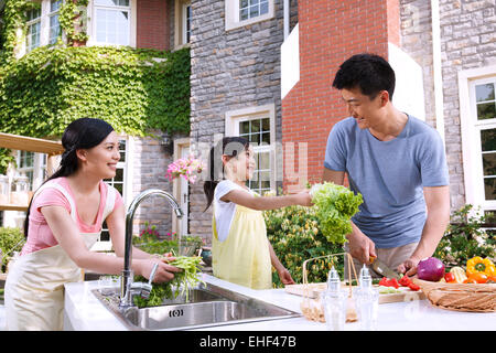 La famiglia felice di tre per preparare gli ingredienti nella cucina esterna Foto Stock