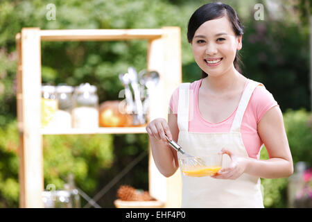 La casalinga che prepara il cibo nella cucina esterna Foto Stock