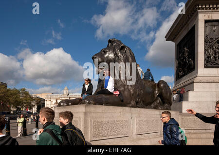 I turisti al Lions in corrispondenza della base della colonna di Nelson,, Londra Foto Stock