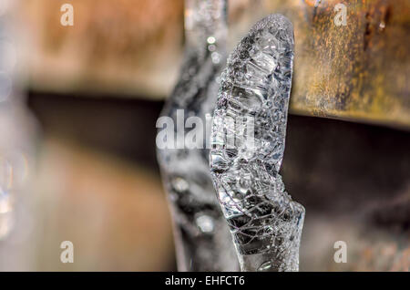 Due ghiaccioli sul tetto, appendere il vecchio tubo di scolo. Stalattiti di ghiaccio formato sul grunge metallo arrugginito. Foto Stock