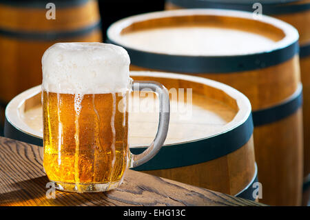 Bicchiere di birra con vecchie botti in legno Foto Stock