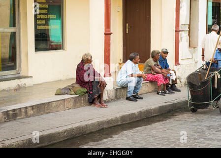 Cuba Santa Clara street scene vecchi uomini donne seduta sedersi sul marciapiede marciapiede passo del furniture store shop spazzatrice stradale Foto Stock