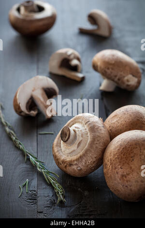 Fresh deliziosi funghi champignon rosmarino decorato su sfondo di legno Foto Stock