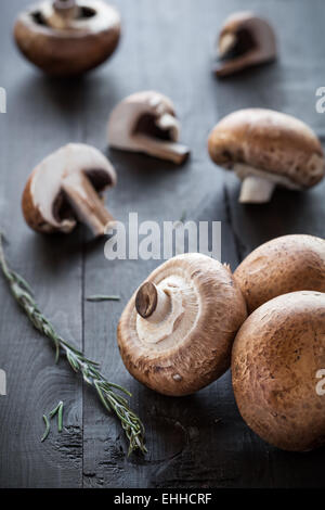 Fresh deliziosi funghi champignon rosmarino decorato su sfondo di legno Foto Stock