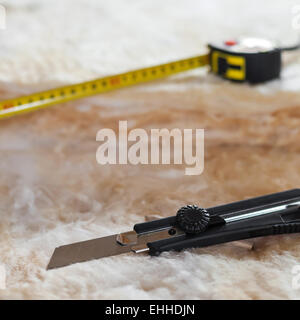 Metro a nastro e il coltello sulla lana minerale, primo piano Foto Stock