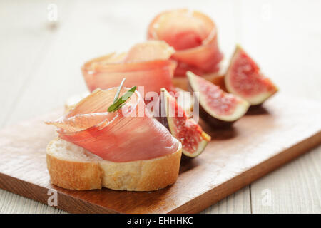 Crostini con prosciutto e fichi sul pannello di legno Foto Stock