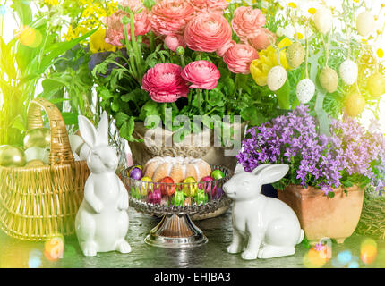 Torta di Pasqua, fiori di primavera, uova e Bunny. Festosa decorazione della casa. In stile retrò tonica immagine con perdite della luce Foto Stock