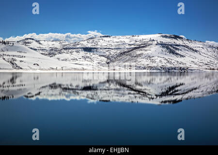 La riflessione di montagne innevate che circonda parzialmente congelato blu Mesa serbatoio vicino Gunnison Colorado USA Foto Stock