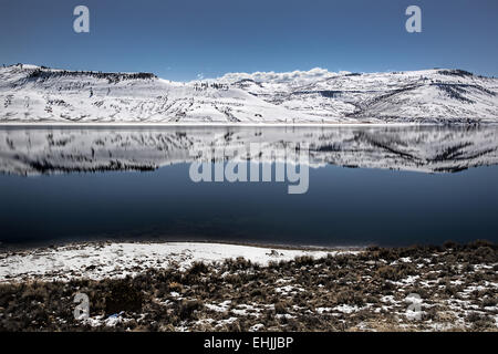 La riflessione di montagne innevate che circonda parzialmente congelato blu Mesa serbatoio vicino Gunnison Colorado USA Foto Stock
