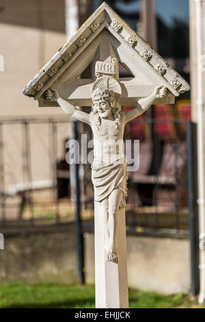 Una rappresentazione in pietra di Gesù Cristo sulla croce su una lapide in un cimitero Foto Stock