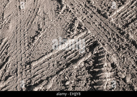 Texture di sfondo di colore marrone scuro sporco su strada con tracce di pneumatici Foto Stock