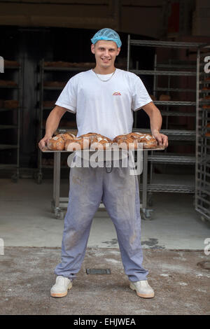 Baker tenendo un vassoio di pane appena sfornato Foto Stock