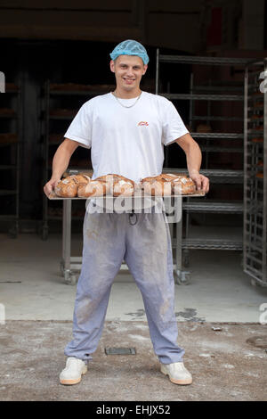 Baker tenendo un vassoio di pane appena sfornato Foto Stock