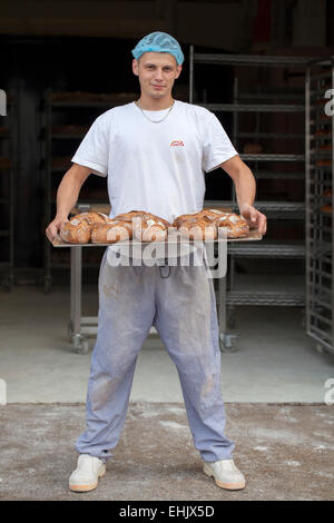 Baker tenendo un vassoio di pane appena sfornato Foto Stock