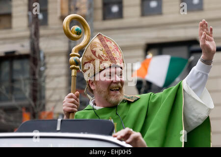 Un irlandese bandiera tricolore onde in background come 'St. Patrick", interpretato da Sean McLaughlin di Lexington, onde la folla durante la trentaseiesima edizione Alltech Lexington il giorno di San Patrizio Parade di Sabato, Marzo 14, 2015 in Lexington, KY, Stati Uniti d'America. Sebbene non sia una vacanza legale nella maggior parte del paese, la festa di San Patrizio è ampiamente celebrato negli Stati Uniti come un riconoscimento di irlandesi e irlandesi di cultura americana con il primo americano celebrazione in onore di Irlanda primario del santo patrono di prendere posto nel 1737. (Apex MediaWire Foto di Billy Suratt) Foto Stock