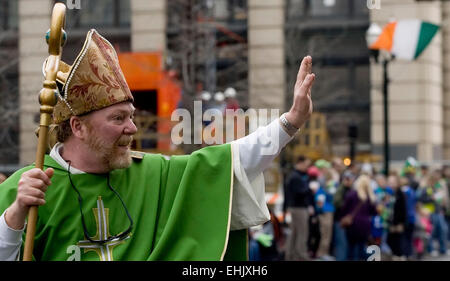 Un irlandese bandiera tricolore onde in background come 'St. Patrick", interpretato da Sean McLaughlin di Lexington, onde la folla durante la trentaseiesima edizione Alltech Lexington il giorno di San Patrizio Parade di Sabato, Marzo 14, 2015 in Lexington, KY, Stati Uniti d'America. Sebbene non sia una vacanza legale nella maggior parte del paese, la festa di San Patrizio è ampiamente celebrato negli Stati Uniti come un riconoscimento di irlandesi e irlandesi di cultura americana con il primo americano celebrazione in onore di Irlanda primario del santo patrono di prendere posto nel 1737. (Apex MediaWire Foto di Billy Suratt) Foto Stock