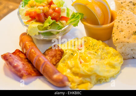 La prima colazione con pancetta, uova, salsiccia, insalata e pane focaccia Foto Stock