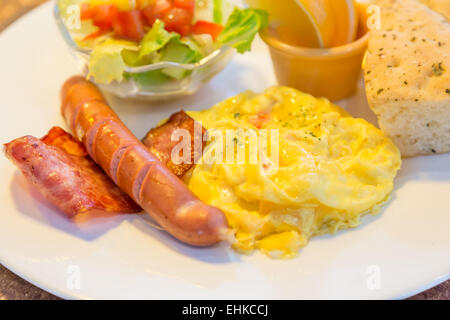 La prima colazione con pancetta, uova, salsiccia, insalata e pane focaccia Foto Stock