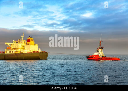 Rimorchiatore tirando la nave cisterna in mare al mattino. Foto Stock