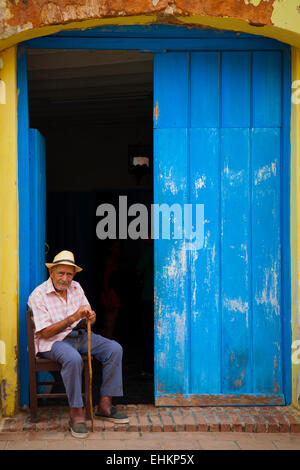 Un vecchio uomo si siede in un portale in Trinidad, Cuba Foto Stock