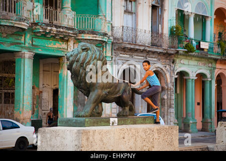 Un bambino gioca su una statua di Lion sul Paseo del Prado, Havana, Cuba Foto Stock