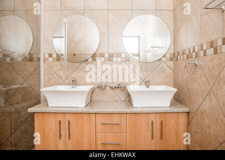 L'interno di un bagno di una nuovissima casa, mostrando i doppi lavandini, specchi e box doccia. Foto Stock