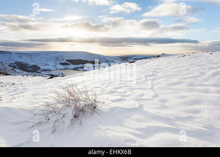 Tramonto dietro la neve derive e erba Saddleworth Moor - guardando fuori verso Manchester. Foto Stock