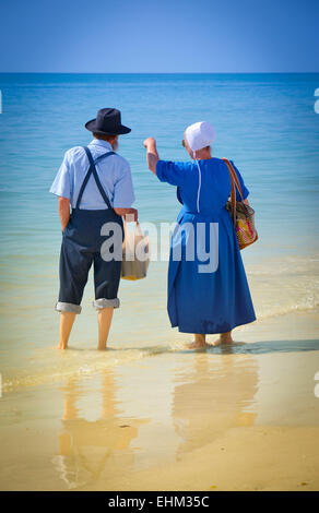 Amish giovane vestito nel loro modo tradizionale pagaia in shallow surf a Siesta Key Beach a Sarasota, FL Foto Stock