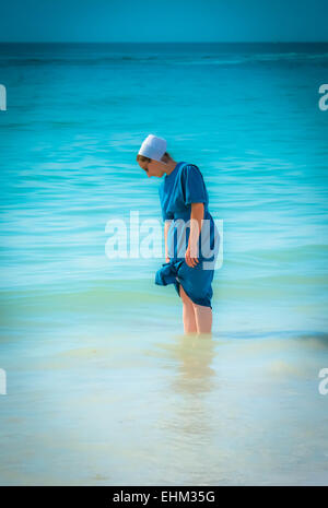 Una donna Amish, vestito in modo tradizionale pagaia in shallow surf a Siesta Key Beach a Sarasota, FL Foto Stock