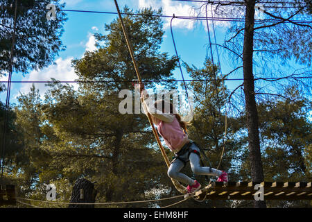 Una bambina completando un corso presso Parco avventura Foto Stock