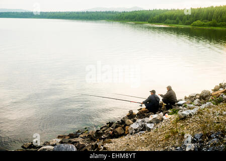 Uomini caucasici la pesca in lago rurale Foto Stock