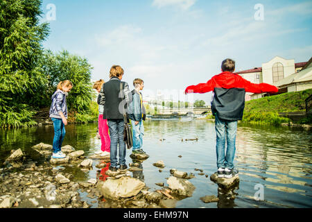 Bambini caucasici giocando sulle rocce in fiume Foto Stock