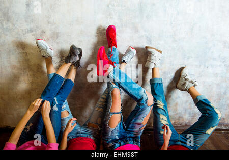 Donne caucasici ammirando le loro sneakers contro la parete Foto Stock