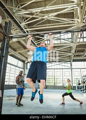 Atleta facendo pull-up nella palestra di magazzino Foto Stock